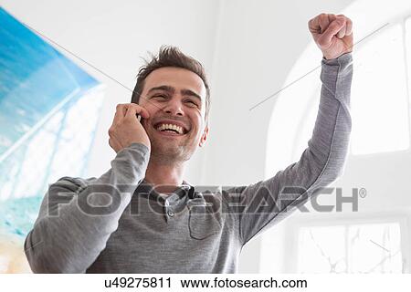 Stock Image - Mature man on telephone call, arm raised. Fotosearch