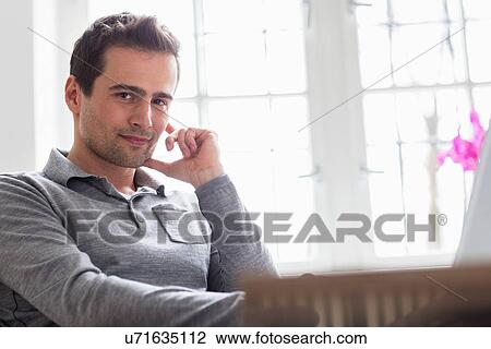 Stock Image - Mature man sitting relaxing, looking at camera. Fotosearch