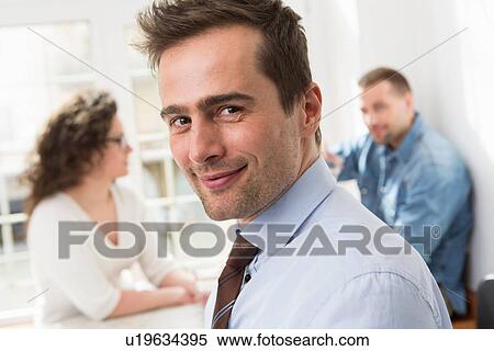 Stock Photography - Mature man smiling at camera, mid adults in background. Fotosearch