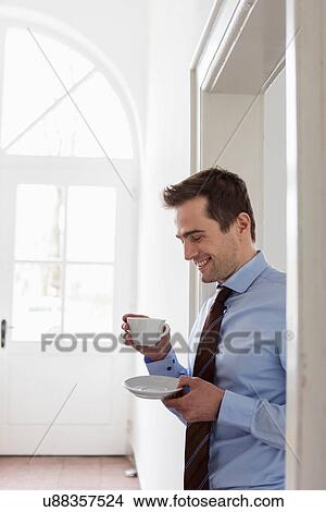 Picture - Mature man wearing shirt and tie holding cup of coffee. Fotosearch