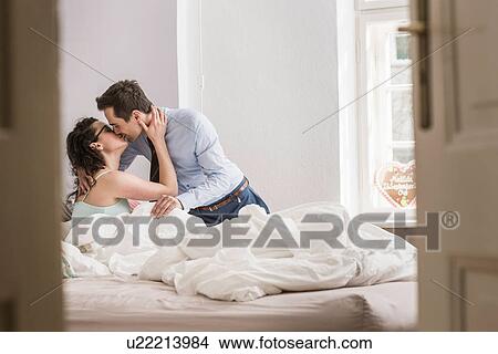 Mid adult couple kissing on bed View Large Photo Image Picture - Mid adult couple kissing on bed. Fotosearch