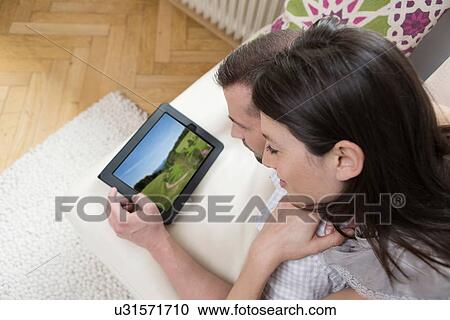 Mid adult couple looking at digital tablet together View Large Photo Image Stock Image - Mid adult couple looking at digital tablet together. Fotosearch