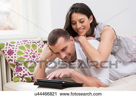 Mid adult couple looking at digital tablet together View Large Photo Image Stock Image - Mid adult couple looking at digital tablet together. Fotosearch