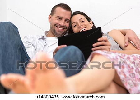 Mid adult couple looking at digital tablet together View Large Photo Image Stock Photography - Mid adult couple looking at digital tablet together. Fotosearch