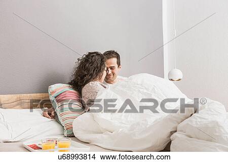 Mid adult couple lying in bed, breakfast on tray View Large Photo Image Picture - Mid adult couple lying in bed, breakfast on tray. Fotosearch