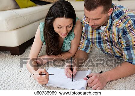 Mid adult couple lying on floor sketching house plans View Large Photo Image Stock Photo - Mid adult couple lying on floor sketching house plans. Fotosearch