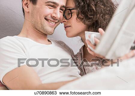 Mid adult couple reading newspaper in bed, face to face View Large Photo Image Stock Image - Mid adult couple reading newspaper in bed, face to face. Fotosearch
