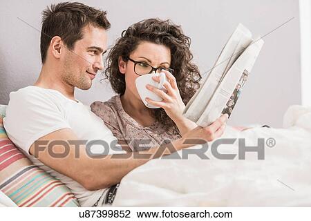 Mid adult couple reading newspaper in bed, drinking coffee View Large Photo Image Stock Image - Mid adult couple reading newspaper in bed, drinking coffee. Fotosearch