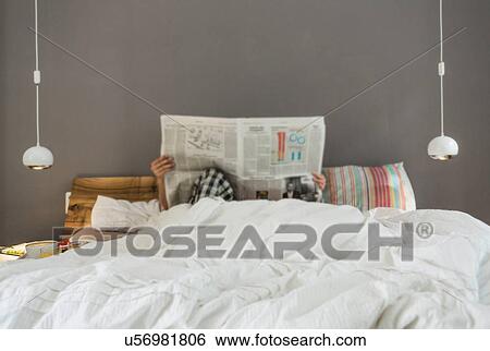 Mid adult couple reading newspaper in bed, faces obscured View Large Photo Image Stock Photograph - Mid adult couple reading newspaper in bed, faces obscured. Fotosearch