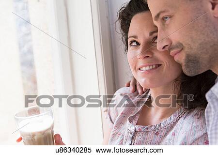 Mid adult couple sitting at window View Large Photo Image Stock Photography - Mid adult couple sitting at window. Fotosearch