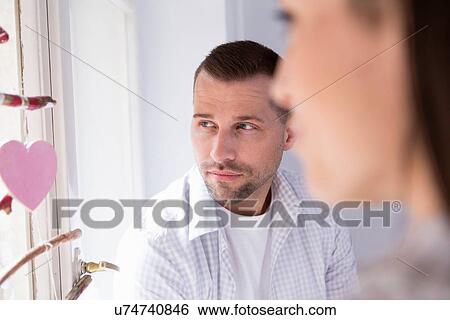 Mid adult couple sitting in window seat View Large Photo Image Stock Photograph - Mid adult couple sitting in window seat. Fotosearch
