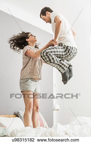 Mid adult couple wearing pyjamas jumping on bed View Large Photo Image Stock Image - Mid adult couple wearing pyjamas jumping on bed. Fotosearch