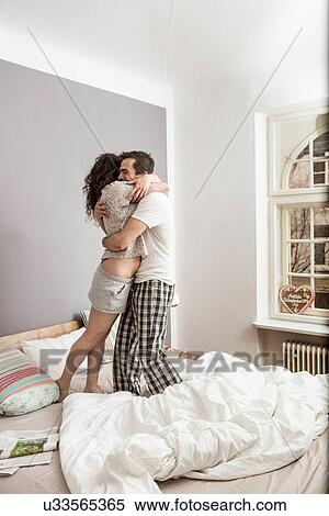 Mid adult couple wearing pyjamas standing on bed hugging View Large Photo Image Stock Photography - Mid adult couple wearing pyjamas standing on bed hugging. Fotosearch