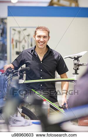 Mid adult man in repair shop with bicycle View Large Photo Image Stock Image - Mid adult man in repair shop with bicycle. Fotosearch
