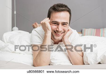 Mid adult man lying on front on bed View Large Photo Image Stock Image - Mid adult man lying on front on bed. Fotosearch