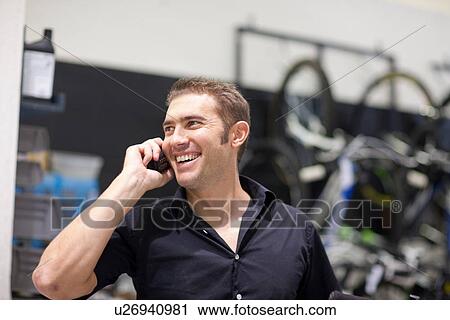 Mid adult man on cellphone in bike shop View Large Photo Image Stock Image - Mid adult man on cellphone in bike shop. Fotosearch