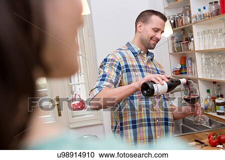 Stock Image - Mid adult man pouring glass of wine. Fotosearch