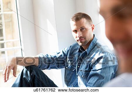 Stock Image - Mid adult man wearing denim shirt. Fotosearch