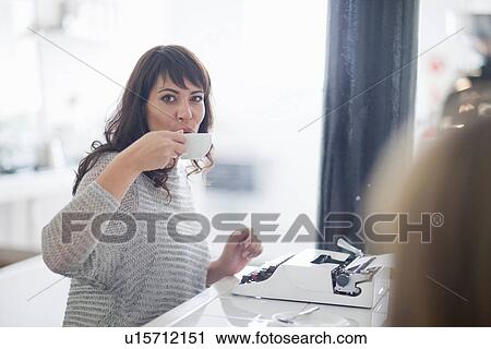 Mid adult woman drinking coffee with typewriter View Large Photo Image Stock Image - Mid adult woman drinking coffee with typewriter. Fotosearch