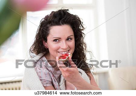 Mid adult woman eating jam croissant View Large Photo Image Picture - Mid adult woman eating jam croissant. Fotosearch
