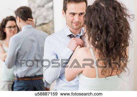 Mid adult woman helping man to fasten tie View Large Photo Image Stock Photo - Mid adult woman helping man to fasten tie. Fotosearch