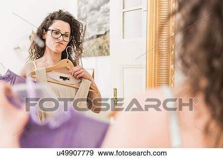Mid adult woman holding up dress in front of mirror View Large Photo Image Stock Photo - Mid adult woman holding up dress in front of mirror. Fotosearch