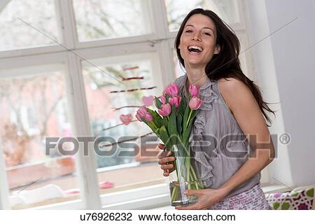 Mid adult woman holding vase of pink flowers View Large Photo Image Stock Image - Mid adult woman holding vase of pink flowers. Fotosearch