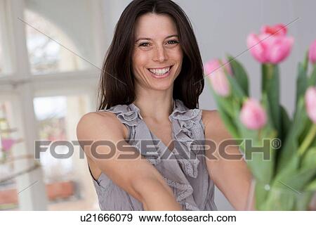 Mid adult woman holding vase of pink flowers View Large Photo Image Stock Photo - Mid adult woman holding vase of pink flowers. Fotosearch