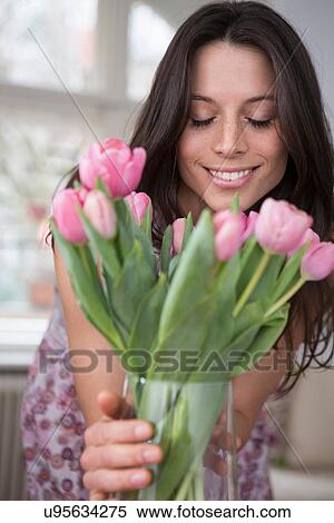 Mid adult woman holding vase of pink flowers View Large Photo Image Stock Photography - Mid adult woman holding vase of pink flowers. Fotosearch