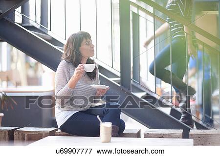Stock Photo - Mid adult woman in cafe with coffee. Fotosearch
