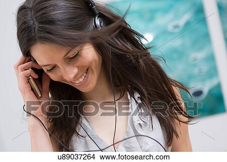 Mid adult woman listening to music through headphones View Large Photo Image Picture - Mid adult woman listening to music through headphones. Fotosearch