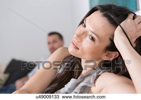 Mid adult woman with hand in hair, man in background View Large Photo Image Stock Image - Mid adult woman with hand in hair, man in background. Fotosearch