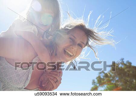 Picture - Mother giving daughter piggy back. Fotosearch