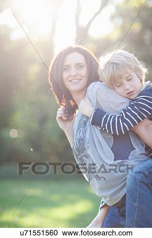 Mother giving son piggyback View Large Photo Image Stock Image - Mother giving son piggyback. Fotosearch