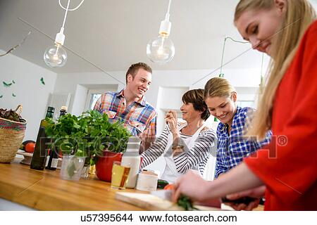 Picture - Mother with grown up children preparing food in kitchen. Fotosearch
