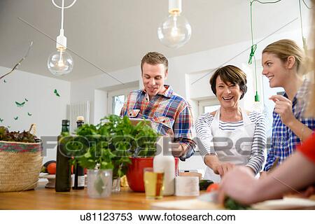 Mother with grown up children preparing food in kitchen View Large Photo Image Stock Image - Mother with grown up children preparing food in kitchen. Fotosearch