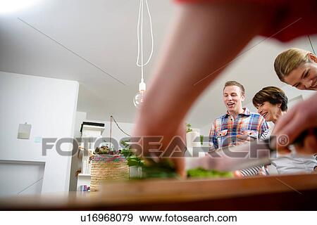Mother with grown up children preparing food in kitchen View Large Photo Image Stock Photo - Mother with grown up children preparing food in kitchen. Fotosearch