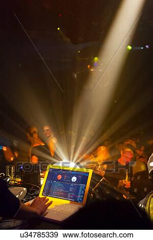 Stock Photo - Nightclub scene with people dancing, disc jockey mixing desk with computer. Fotosearch