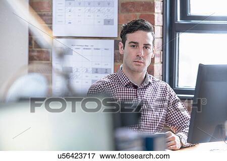 Office worker sitting at desk, portrait View Large Photo Image Stock Photo - Office worker sitting at desk, portrait. Fotosearch