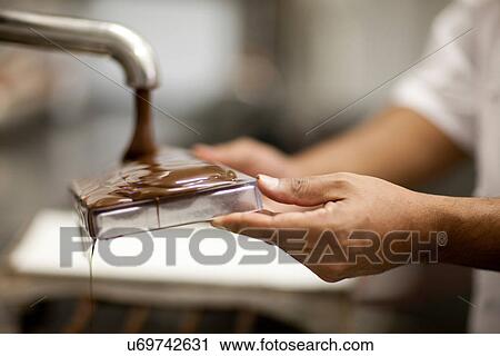 Stock Image - Person filling mould with melted chocolate. Fotosearch