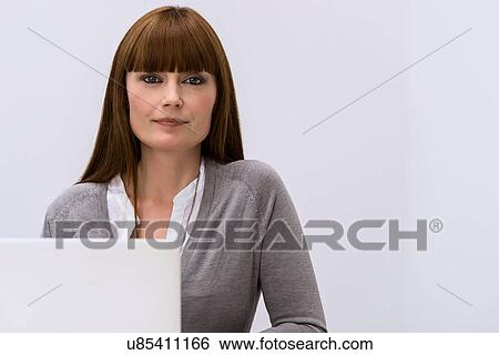 Stock Photograph - Portrait of mid adult woman at behind laptop. Fotosearch