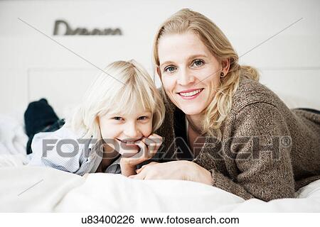 Portrait of mother and son lying on bed View Large Photo Image Stock Photograph - Portrait of mother and son lying on bed. Fotosearch