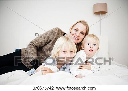 Portrait of mother and two young sons lying on bed View Large Photo Image Stock Image - Portrait of mother and two young sons lying on bed. Fotosearch