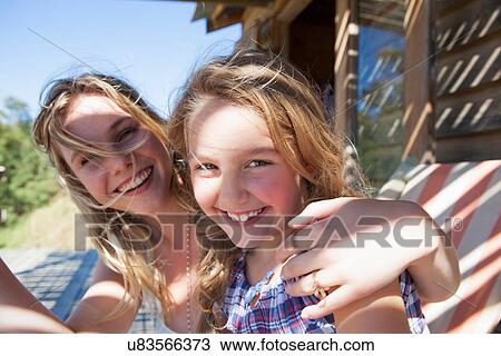 Stock Image - Portrait of mother with arm around daughter. Fotosearch