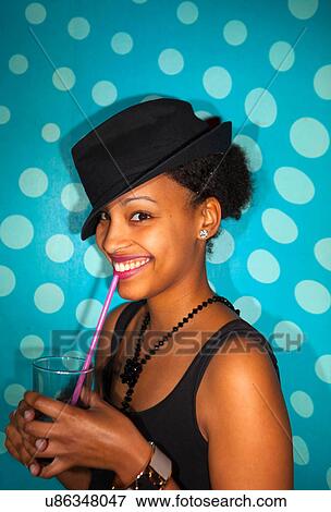 Portrait of young adult woman with mixed race ethnicity smiling and holding drinking glass with straw View Large Photo Image Stock Photo - Portrait of young adult woman with mixed race ethnicity smiling and holding drinking glass with straw. Fotosearch
