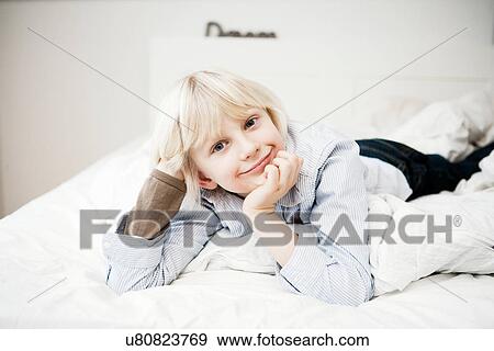 Portrait of young boy lying on bed View Large Photo Image Stock Photo - Portrait of young boy lying on bed. Fotosearch