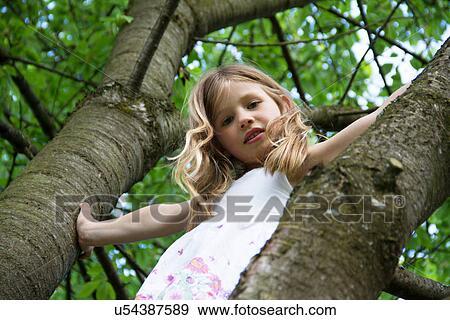 Stock Photo - Portrait of young girl climbing tree. Fotosearch