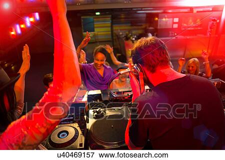 Rear view of disc jockey surrounded by people dancing View Large Photo Image Stock Photo - Rear view of disc jockey surrounded by people dancing. Fotosearch