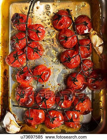 Stock Photography - Roasted vine tomatoes in roasting tin. Fotosearch
