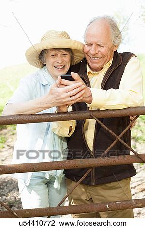 Senior couple smiling at message on mobile phone View Large Photo Image Stock Image - Senior couple smiling at message on mobile phone. Fotosearch